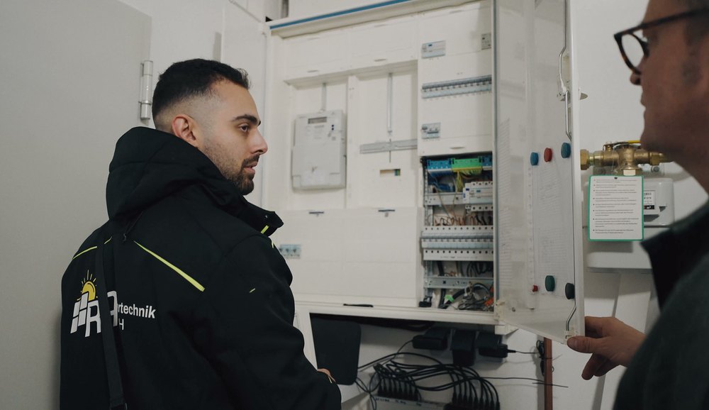 Elektriker vor einem geöffneten Zählerschrank im Gespräch