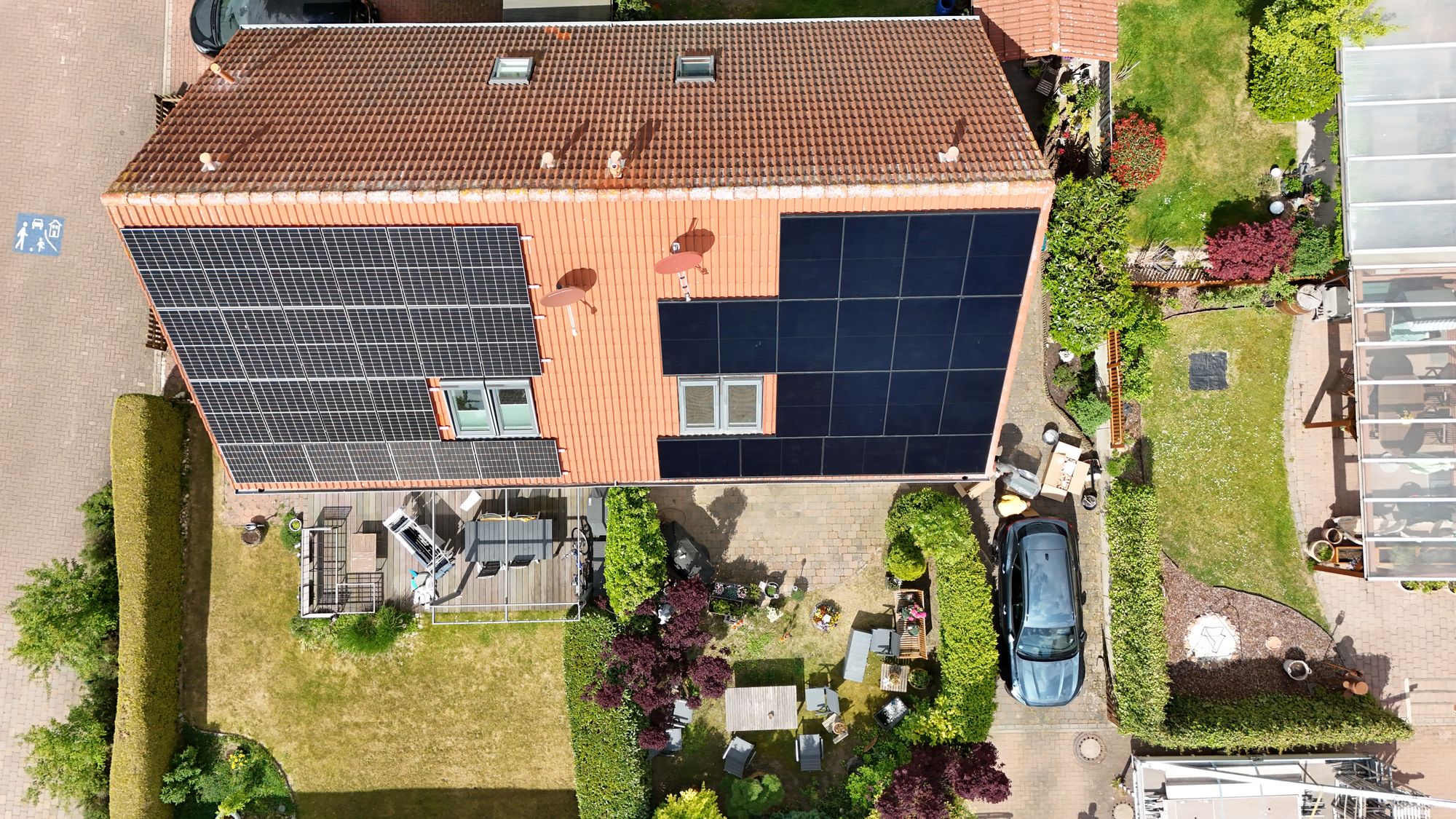 Photovoltaikanlage auf einem orangen Ziegeldach von oben (Drohnenaufnahme)