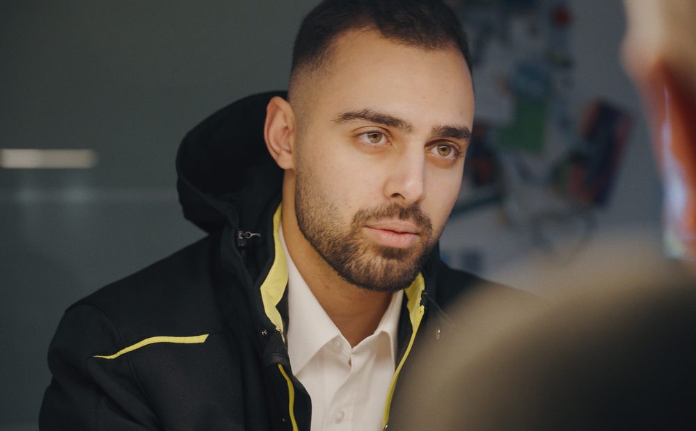 Ali Noureddine aus der Kundenberatung von RA Solartechnik im Gespräch, in schwarzer RA-Jacke über weißem Hemd, vorn unscharf sein Gegenüber