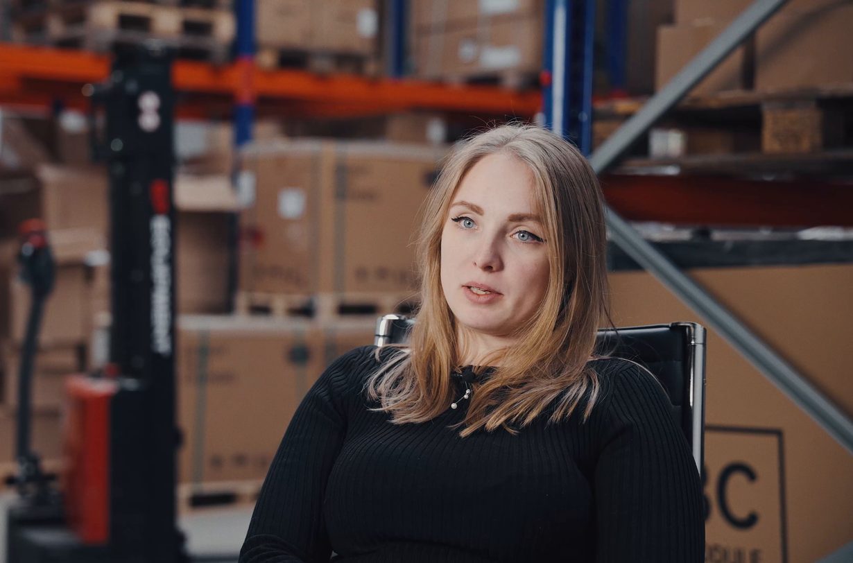 Michelle-Kathrin Börkei von RA Solartechnik im Lager, hinter ihr Regale mit Paletten und Kartons