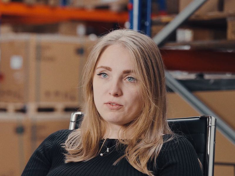 Michelle-Kathrin Börkei aus dem Büro von RA Solartechnik, Porträt im Lager mit Kartons im Hintergrund