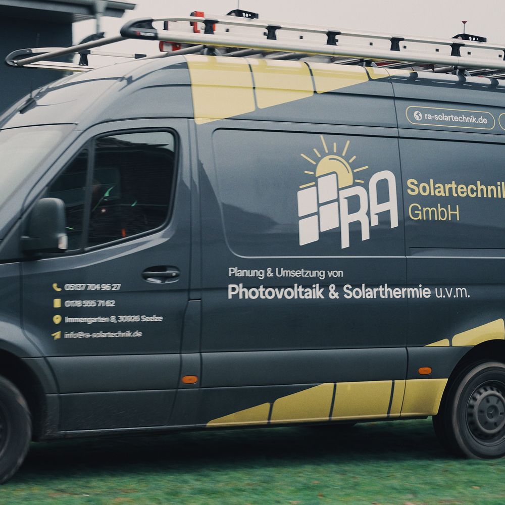 Firmenwagen von RA Solartechnik vor einem Gebäude mit Photovoltaikanlage auf dem Ziegeldach
