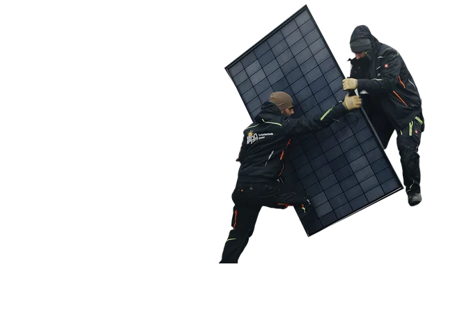 Zwei Monteure tragen ein Solarmodul über ein mit Modulen belegtes Dach