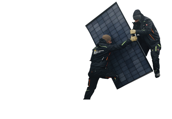 Zwei Monteure tragen ein Solarmodul über ein mit Modulen belegtes Dach