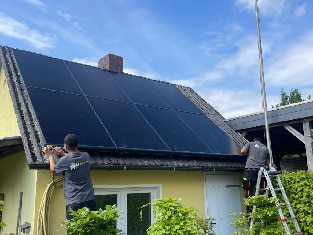 Zwei Monteure von RA Solartechnik montieren Module auf einem kleinen Dach