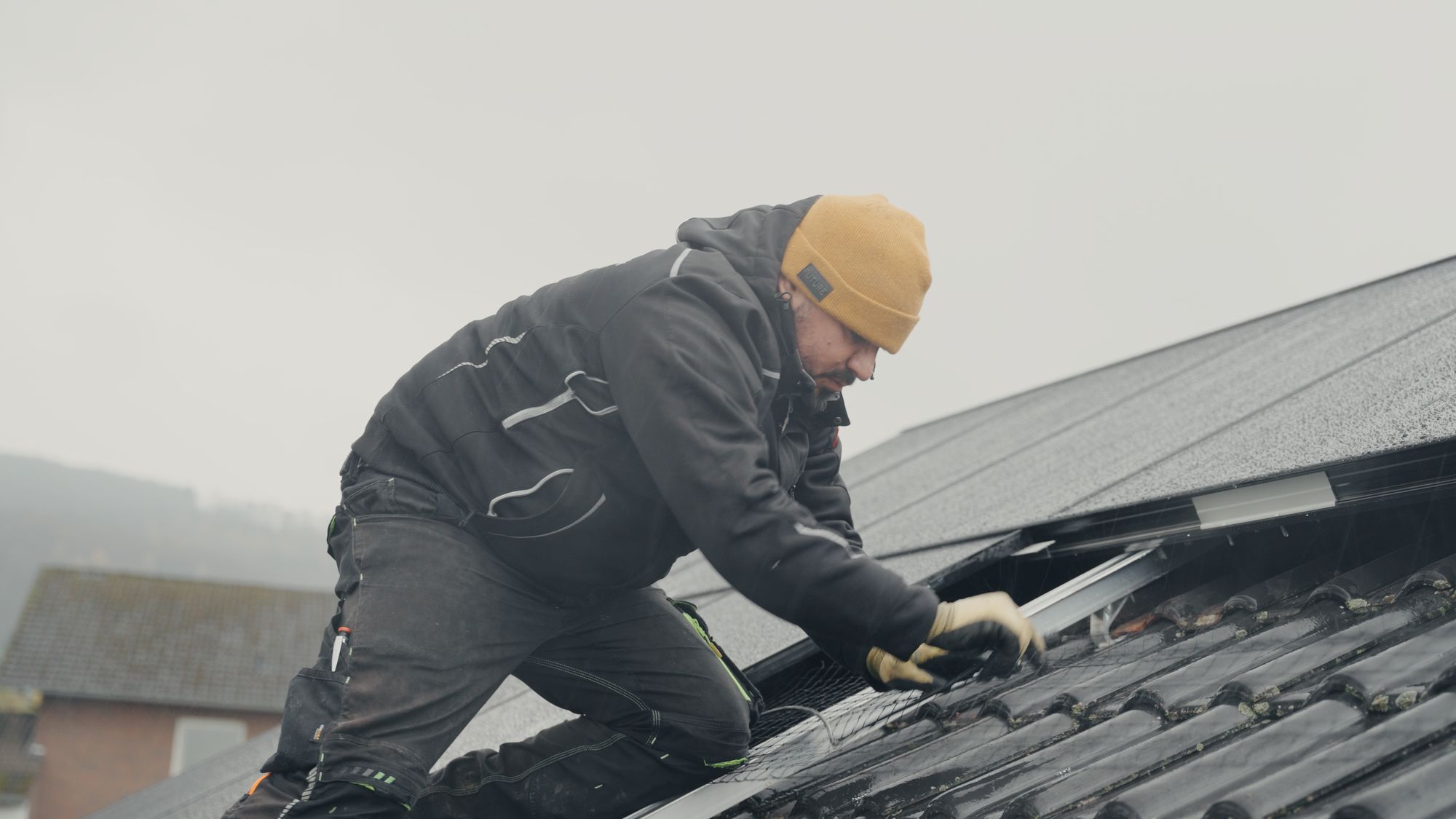 Monteur von RA Solartechnik bereitet auf dem Ziegeldach die Montage der schwarzen Solarmodule vor