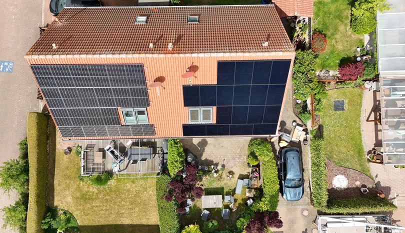 Photovoltaikanlage auf einem orangen Ziegeldach von oben (Drohnenaufnahme)
