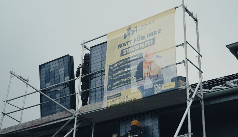 Baugerüst mit RA-Solartechnik-Werbebanner an einem Haus mit Solarmodulen
