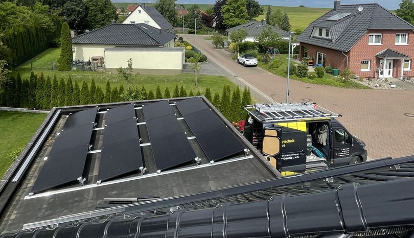 Drohnenaufnahme: Photovoltaikanlage auf einem Dach, davor der RA-Firmenwagen