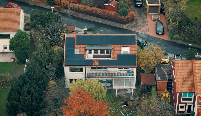 Photovoltaikanlage auf einem roten Ziegeldach mit Gaube (Drohnenaufnahme)
