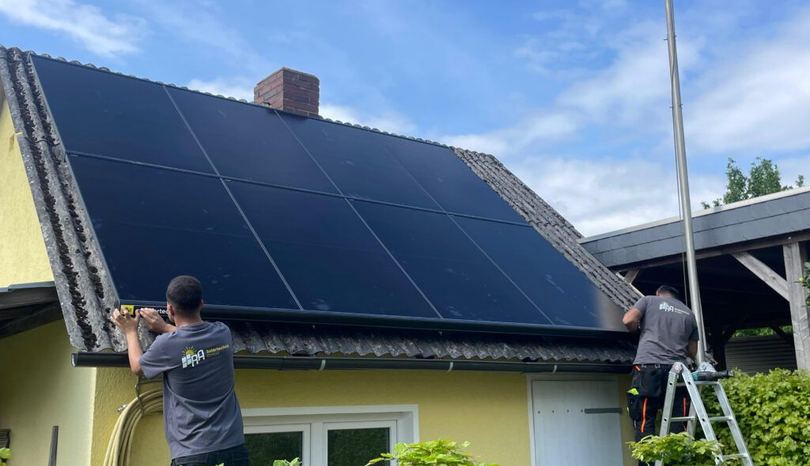 Zwei Monteure von RA Solartechnik montieren Module auf einem kleinen Dach