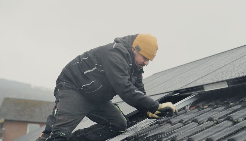 Monteur von RA Solartechnik bereitet auf dem Ziegeldach die Montage der schwarzen Solarmodule vor