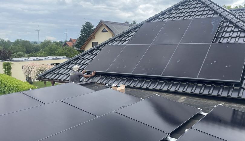 Solarmodule auf einem Ziegeldach in Holle, im Hintergrund Windräder