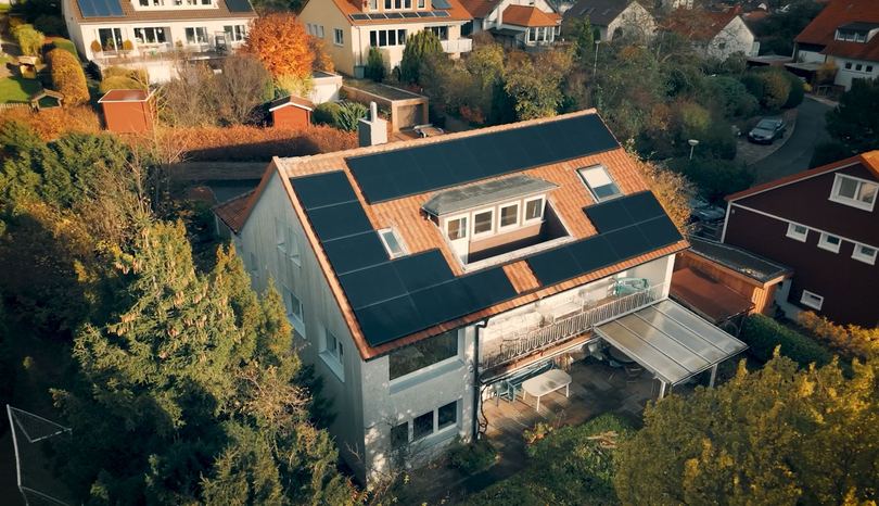 Wohnhaus mit Solarmodulen auf beiden Dachseiten (Drohnenaufnahme)