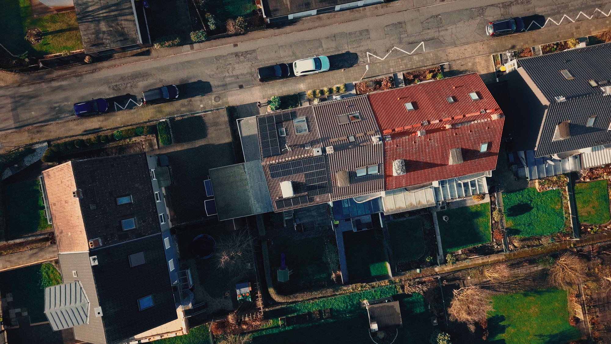 Luftaufnahme senkrecht von oben: Reihenhäuser einer Wohnsiedlung, ein Dach mit Solarmodulen belegt