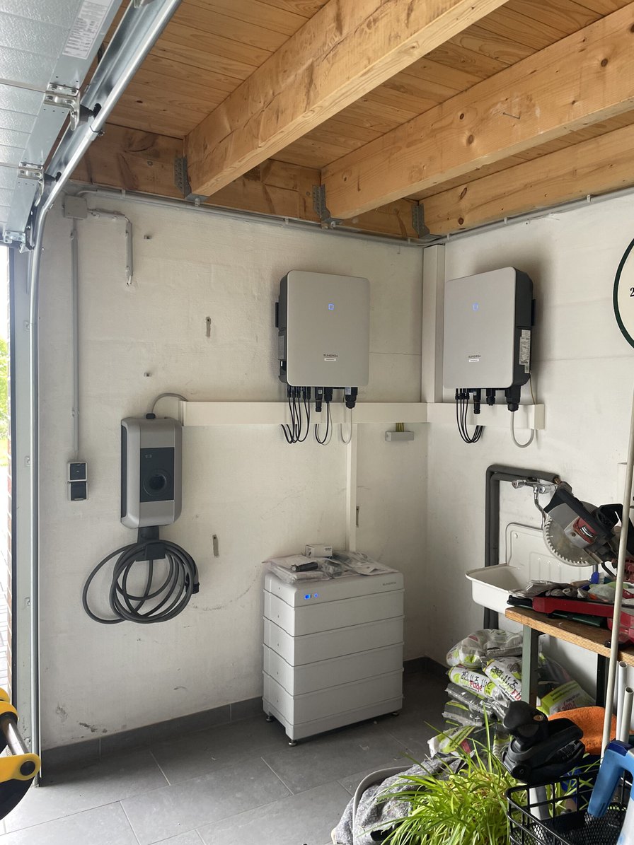 Wallbox, zwei Wechselrichter und Batteriespeicher an der Wand einer Garage